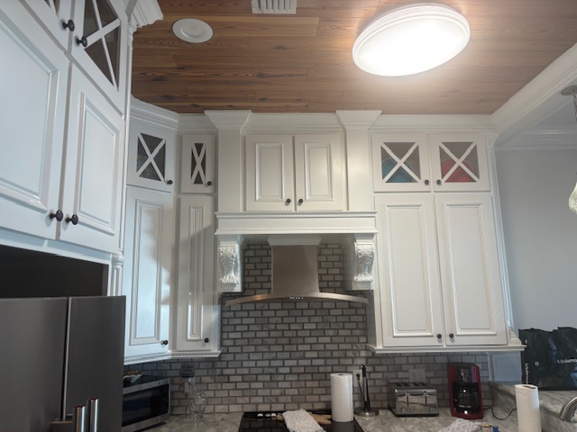 White kitchen cabinetry with stained wood ceiling